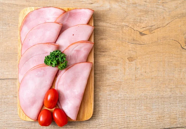 Ahşap tahta üzerinde dilimlenmiş jambon füme