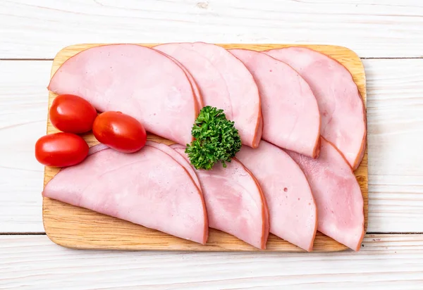 Ahşap tahta üzerinde dilimlenmiş jambon füme