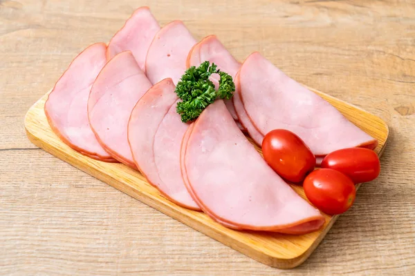 Ahşap tahta üzerinde dilimlenmiş jambon füme