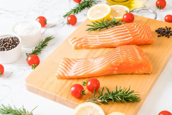 Limon domates Biberiye Biber ve tuz ahşap tahta üzerinde Çiğ somon fileto