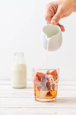 Tay çay buz küpü ile ahşap arka plan üzerinde süt