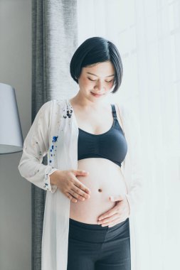 Genç güzel Asyalı hamile kadın ona dokunan karın evde - vintage filtre stili ile seçici odak noktası