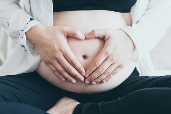 年轻美丽的亚洲孕妇抱着她的手在怀孕的腹部选择性聚焦点与老式过滤器风格的心脏形状 — 图库照片