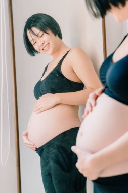 Genç güzel Asyalı hamile kadın ona dokunan karın evde - seçici odak noktası ve vintage tarzı