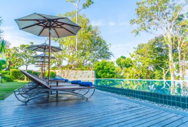 Otelde ve tatil beldesinde yüzme havuzunda güzel şemsiye ve sandalye - tatil kavramı