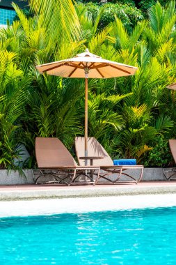 Şemsiye ve sandalye yüzme havuzunda otel ve tatil - tatil tatil kavramı çevresinde