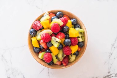 Ahşap kasede taze meyveler (çilek, ahududu, yabanmersini, kivi, mango)