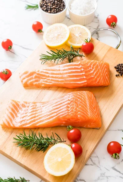 Limon domates Biberiye Biber ve tuz ahşap tahta üzerinde Çiğ somon fileto