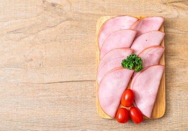 Ahşap tahta üzerinde dilimlenmiş jambon füme