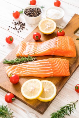 Limon domates Biberiye Biber ve tuz ahşap tahta üzerinde Çiğ somon fileto