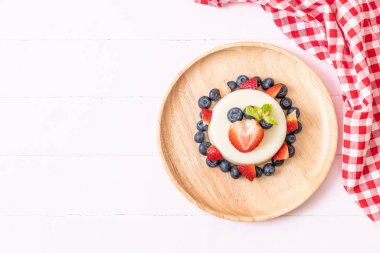 yoğurt puding plaka üzerinde bir yaban mersini ve taze çilek ile
