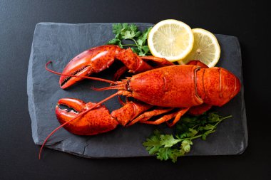 Sebzeli kırmızı ıstakoz ve siyah tabakta limon.