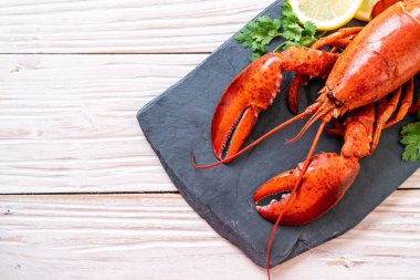 Sebzeli kırmızı ıstakoz ve siyah tabakta limon.