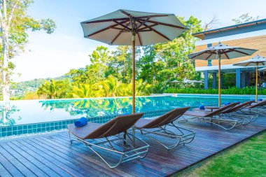 Otelde ve tatil beldesinde yüzme havuzunda güzel şemsiye ve sandalye - tatil kavramı