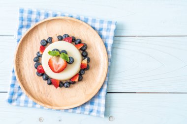 yoğurt puding plaka üzerinde bir yaban mersini ve taze çilek ile