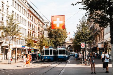 ZURICH, SWITZERLAND - AUG 23, 2018: A tram drives down the center of Bahnhofstrasse while people walk on the sidewalks in Zurich City, Switzerland. clipart