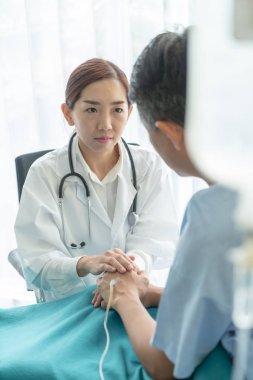 Asyalı kadın doktor onun üst düzey hasta el - seçici odak noktası güven verici