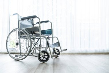 perde ve güneş ışığı ile bir odada boş tekerlekli sandalye