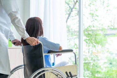 Tekerlekli sandalye ile kıdemli Doktor Asyalı kadın hastayı