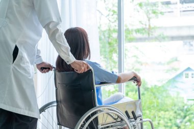 Tekerlekli sandalye ile kıdemli Doktor Asyalı kadın hastayı