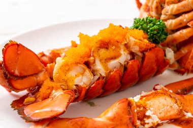 Soslu ıstakoz kuyruklu biftek ve beyaz arka planda karides yumurtaları.