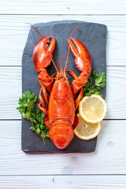 Sebzeli kırmızı ıstakoz ve siyah tabakta limon.