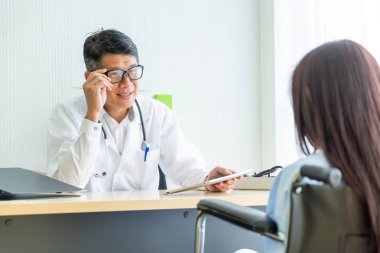 Asyalı doktor ve hasta Danışma ve masada otururken bir şey tartışırken vardır