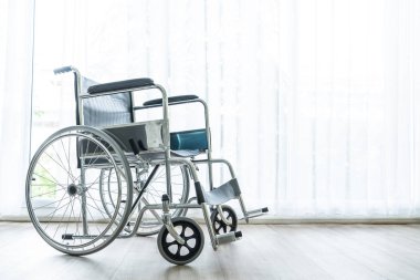 perde ve güneş ışığı ile bir odada boş tekerlekli sandalye