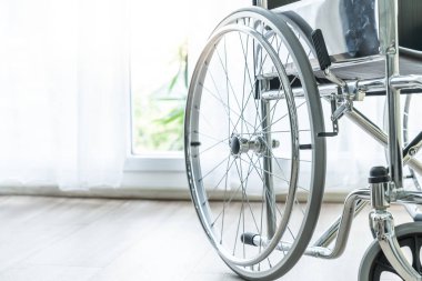 perde ve güneş ışığı ile bir odada boş tekerlekli sandalye