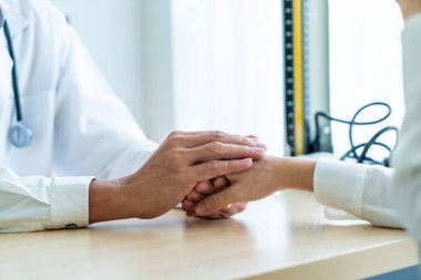 Kıdemli doktor kadın hastasını güven verici el