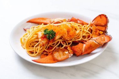 Beyaz tabakta karides yumurtalı ıstakoz spagettisi.