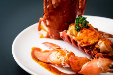 Soslu ıstakoz kuyruklu biftek ve beyaz arka planda karides yumurtaları.