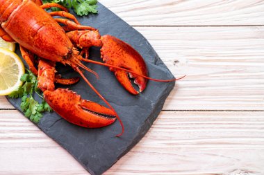 Sebzeli kırmızı ıstakoz ve siyah tabakta limon.