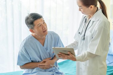 Asya kıdemli hasta hastane yatak kadın doktor - seçici odak noktası ile tartışırken.