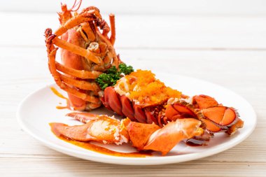 Soslu ıstakoz kuyruklu biftek ve beyaz arka planda karides yumurtaları.