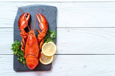 Sebzeli kırmızı ıstakoz ve siyah tabakta limon.