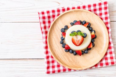 yoğurt puding plaka üzerinde bir yaban mersini ve taze çilek ile