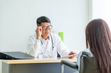 Asyalı doktor ve hasta Danışma ve masada otururken bir şey tartışırken vardır