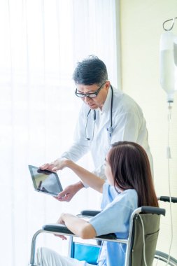 Tekerlekli sandalye ile kıdemli Doktor Asyalı kadın hastayı