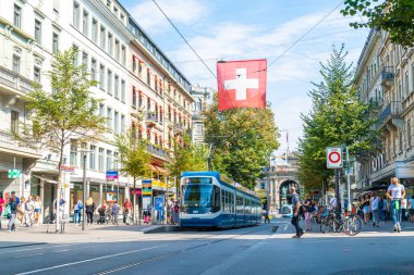 ZURICH, SWITZERLAND - AUG 23, 2018: A tram drives down the center of Bahnhofstrasse while people walk on the sidewalks in Zurich City, Switzerland. clipart