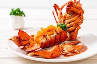 Soslu ıstakoz kuyruklu biftek ve beyaz arka planda karides yumurtaları.