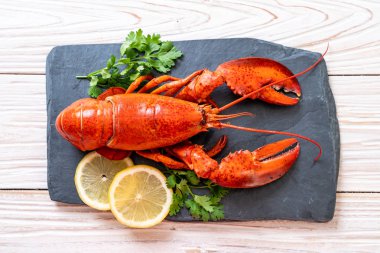 Sebzeli kırmızı ıstakoz ve siyah tabakta limon.