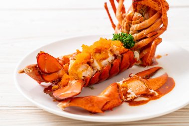 Soslu ıstakoz kuyruklu biftek ve beyaz arka planda karides yumurtaları.