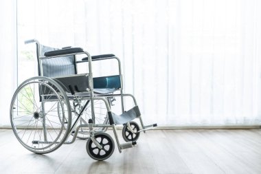 perde ve güneş ışığı ile bir odada boş tekerlekli sandalye