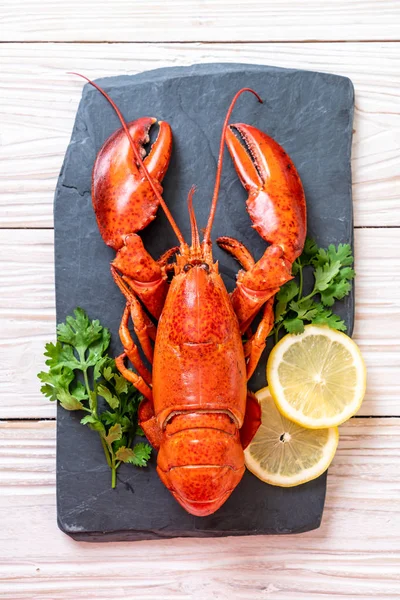 Sebzeli kırmızı ıstakoz ve siyah tabakta limon.