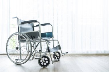 perde ve güneş ışığı ile bir odada boş tekerlekli sandalye