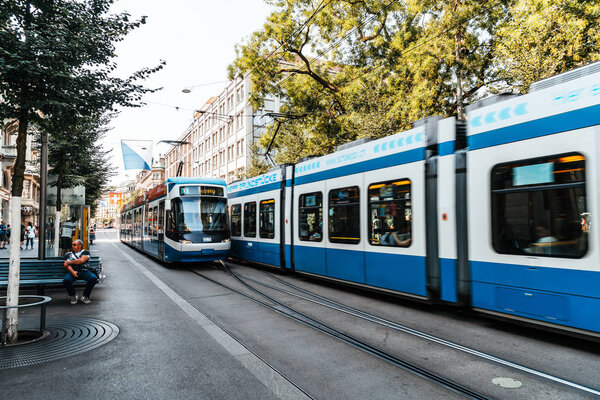 ZURICH, SWITZERLAND - AUG 23, 2018: A tram drives down the center of Bahnhofstrasse while people walk on the sidewalks in Zurich City, Switzerland.