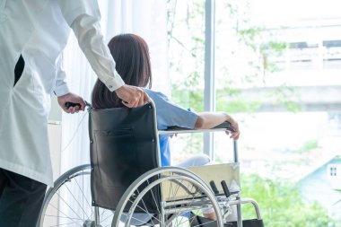 Tekerlekli sandalye ile kıdemli Doktor Asyalı kadın hastayı