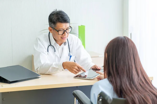 Asian doctor and patient are consultation and discussing something while sitting at the table