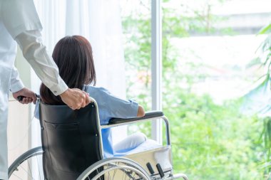 Tekerlekli sandalye ile kıdemli Doktor Asyalı kadın hastayı